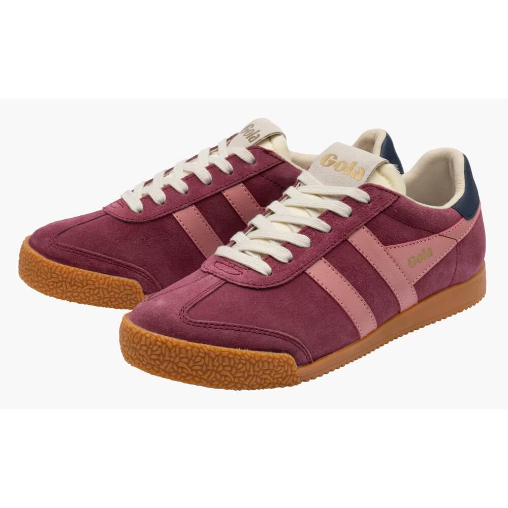A pair of Gola low-top suede sneakers in a deep burgundy colour, featuring light pink side stripes, cream laces, a cream tongue label with gold lettering, and a brown gum sole.