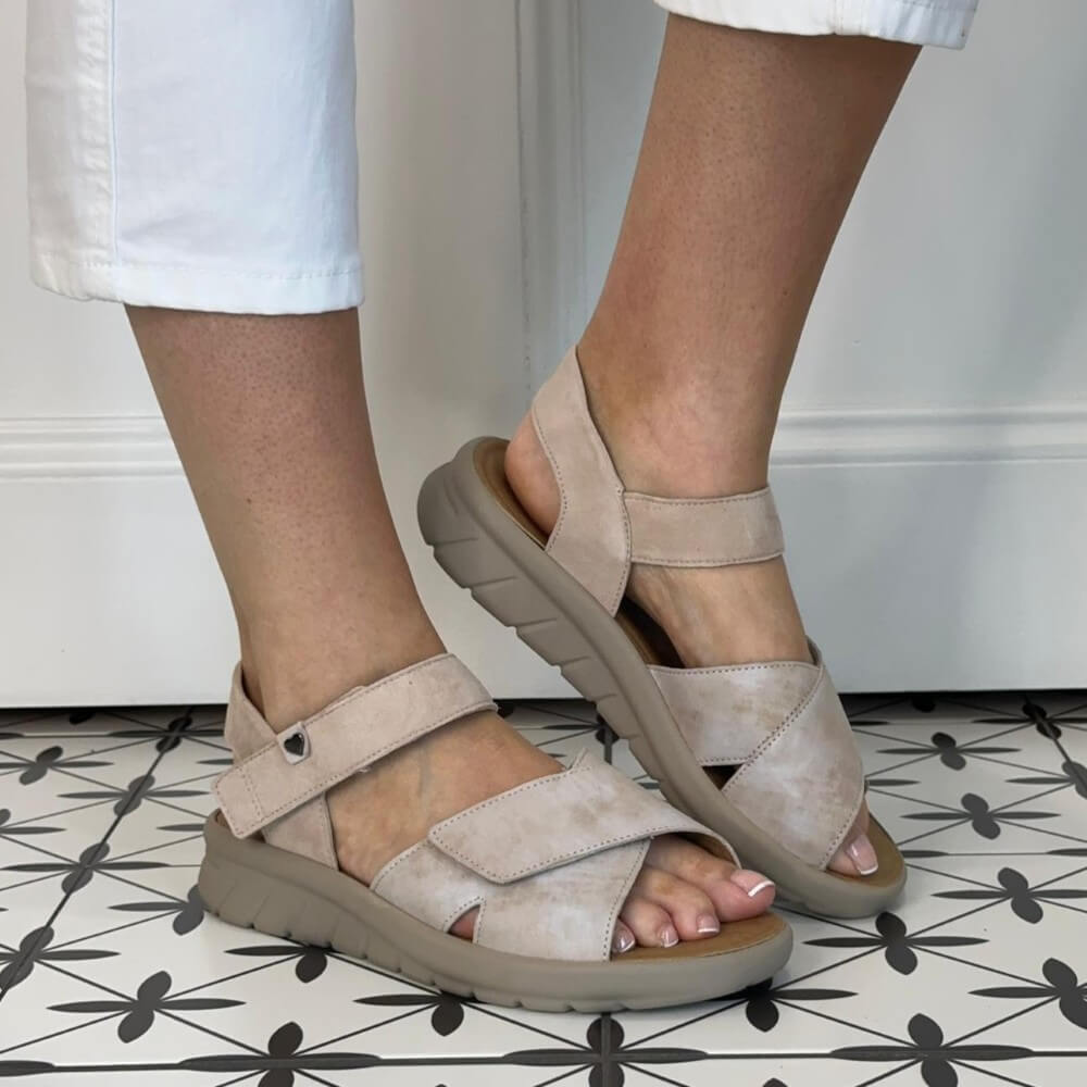 Hartjes Wide K Fit Beige sandals worn on a patterned floor with white pants.