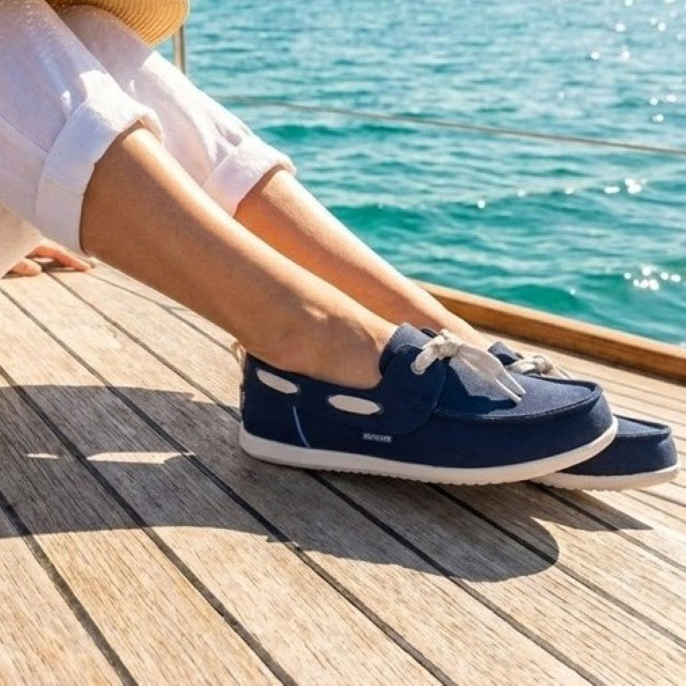 Person wearing heydude navy boat shoes by the sea