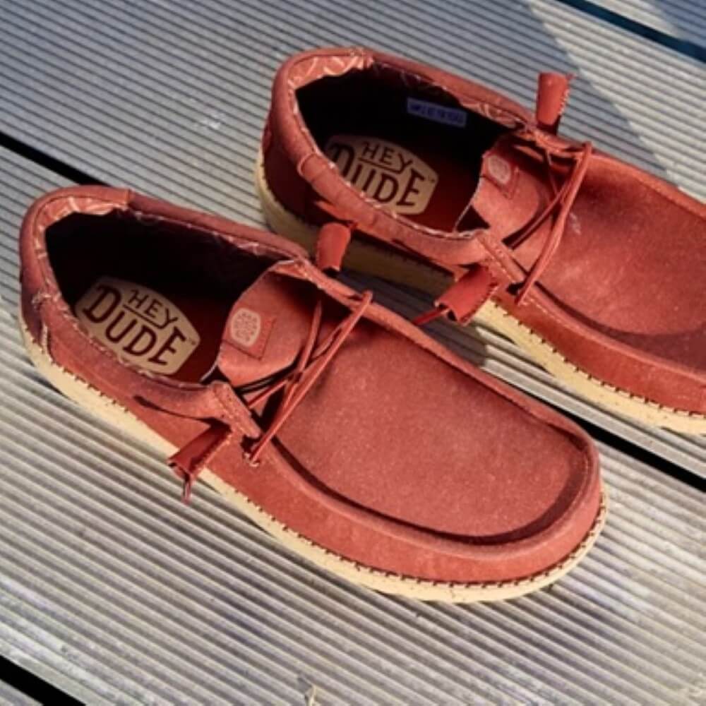 Pair of heydude red shoes with 'Hey Dude' branding on a metallic surface