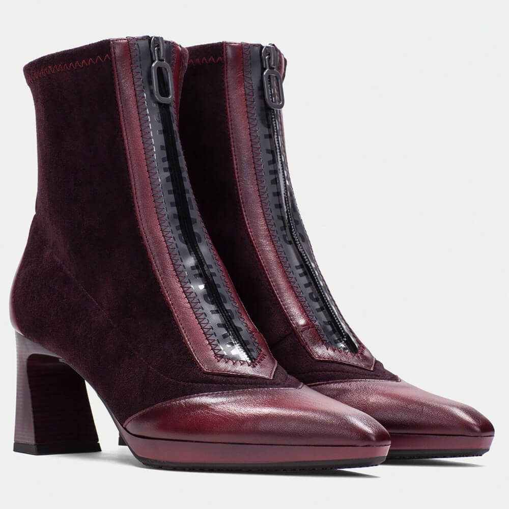 Pair of maroon ankle boots with a zipper on a light gray background