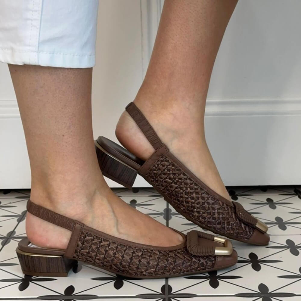 Hispanitas Brown woven sandals worn by a person on a patterned floor.