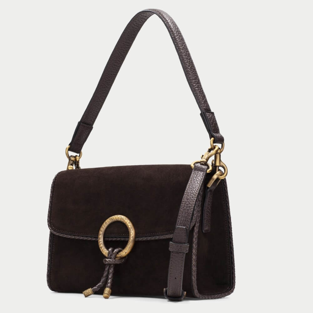 A  Hispanitas dark brown suede shoulder bag with a gold-tone circular ring detail and a matching leather tassel, shown against a light gray background.