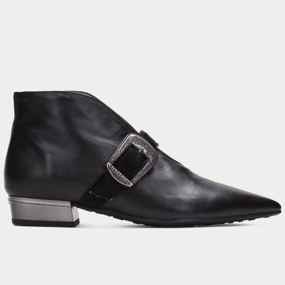 A Hispanitas black leather ankle boot with a pointed toe, a low block heel, and a decorative silver buckle strap across the side, shown in profile against a light grey background.