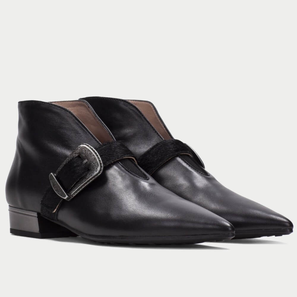 A pair of Hispanitas black leather ankle boots with a pointed toe, a low block heel, and a wide strap across the instep featuring a silver-tone buckle.
