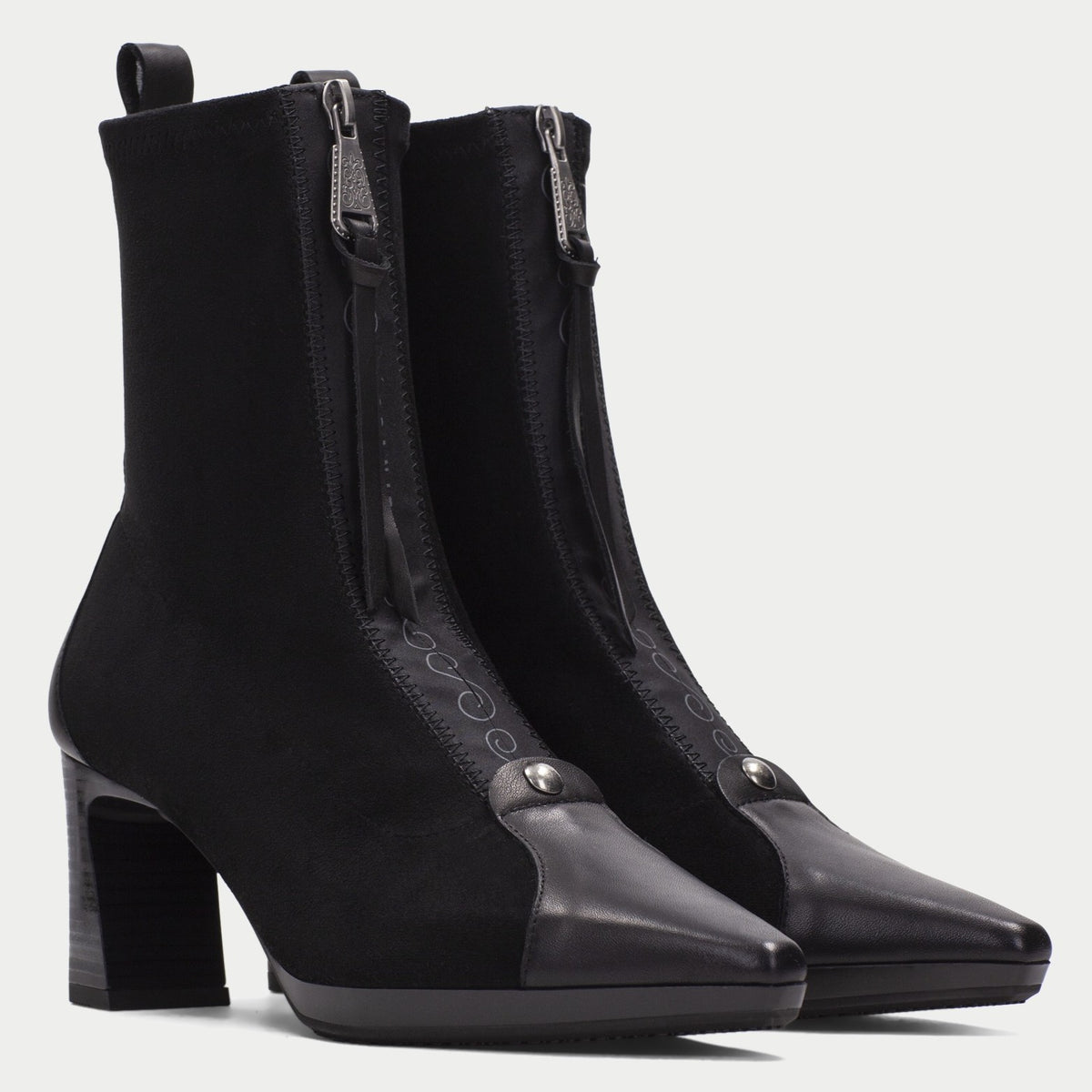 A pair of Hispanitas black ankle boots with a block heel, pointed toe, and silver-tone hardware, with a centre zip, shown against a light grey background.
