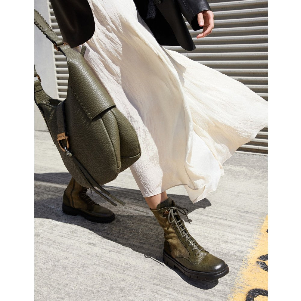 Person wearing green boots and a white skirt with a green backpack on a city street. Green leather boot with a black sole. Hispanitas Hamburg HI254234 Lace-up Leather Boot Army Green