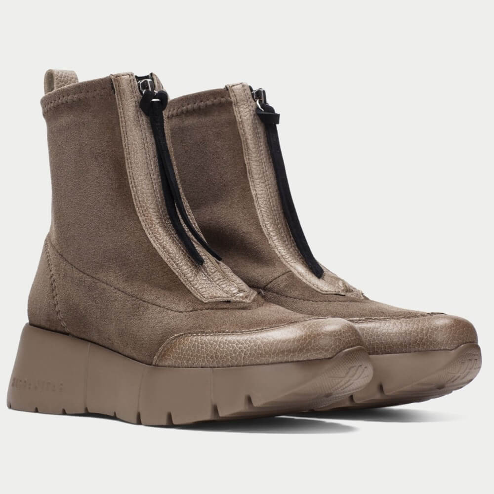 A pair of Hispanitas ankle boots in a taupe brown colour, featuring a pebbled leather upper, a front zipper with brown pull tabs, and a chunky lug sole.