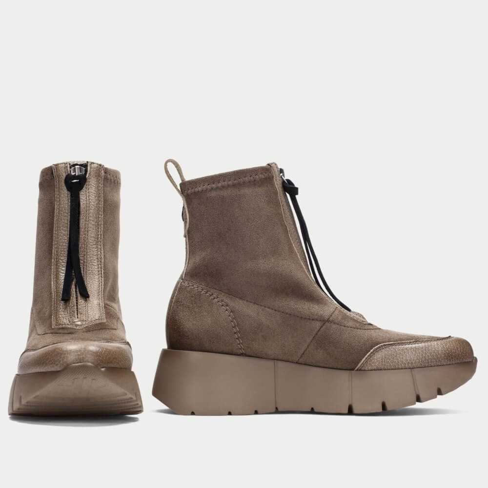 A pair of Hispanitas ankle boots in a taupe brown colour, featuring a pebbled leather upper, a front zipper with brown pull tabs, and a chunky lug sole.