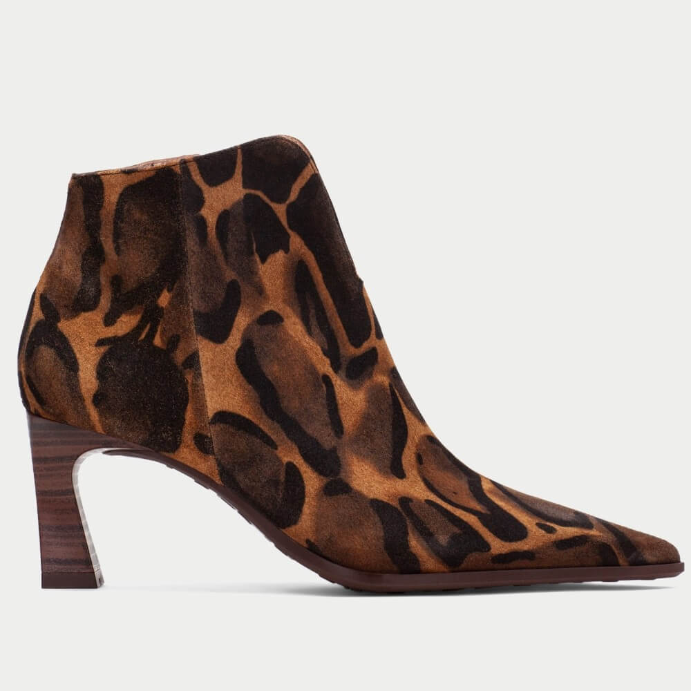 A Hispanitas pointed-toe ankle boot with a brown and black Giraffe leopard print pattern, featuring a chunky dark brown block heel, shown from a side profile on a light grey background.