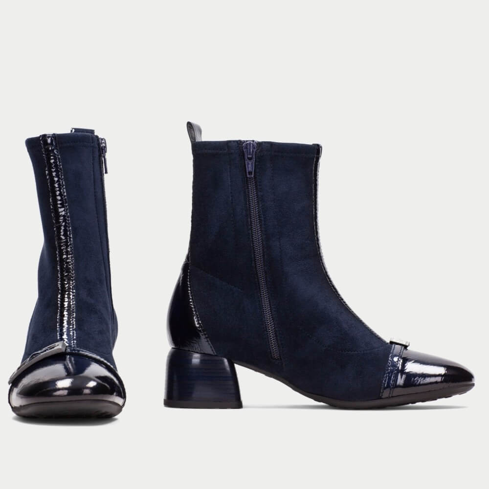A pair of Hispanitas navy blue ankle boots with a mix of suede and patent leather materials, featuring side zippers and block heels, shown against a light gray background.