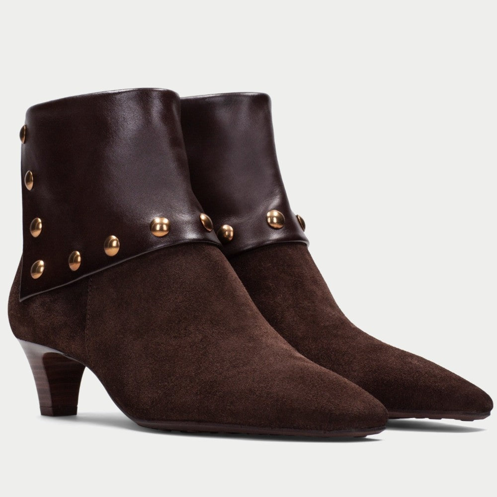 A pair of Hispanitas dark brown suede and leather ankle boots with a pointed toe, a stacked wooden-look heel, and a wide leather cuff embellished with gold-tone studs, shown against a light grey background.
