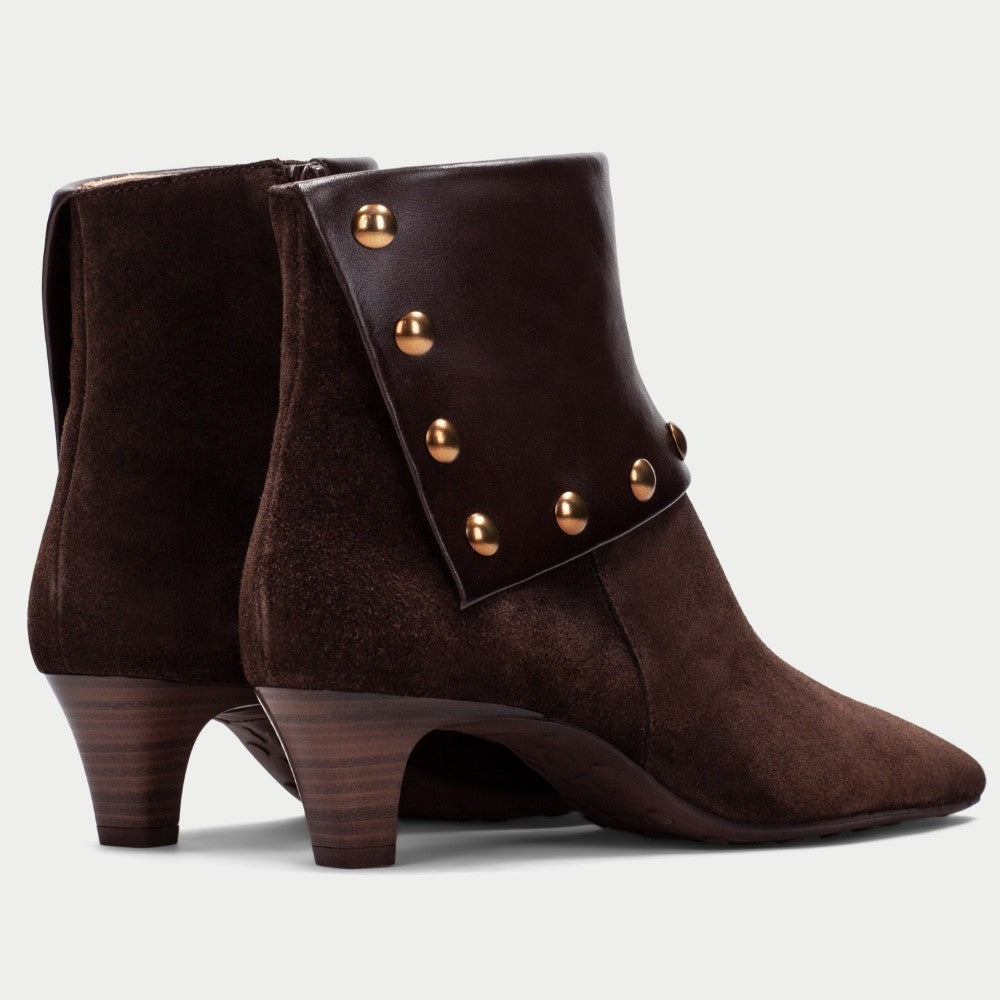 A pair of Hispanitas dark brown suede and leather ankle boots with a pointed toe, a stacked wooden-look heel, and a wide leather cuff embellished with gold-tone studs, shown against a light grey background.