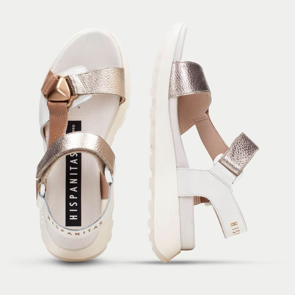 White sandals with rose gold accents on a light gray background