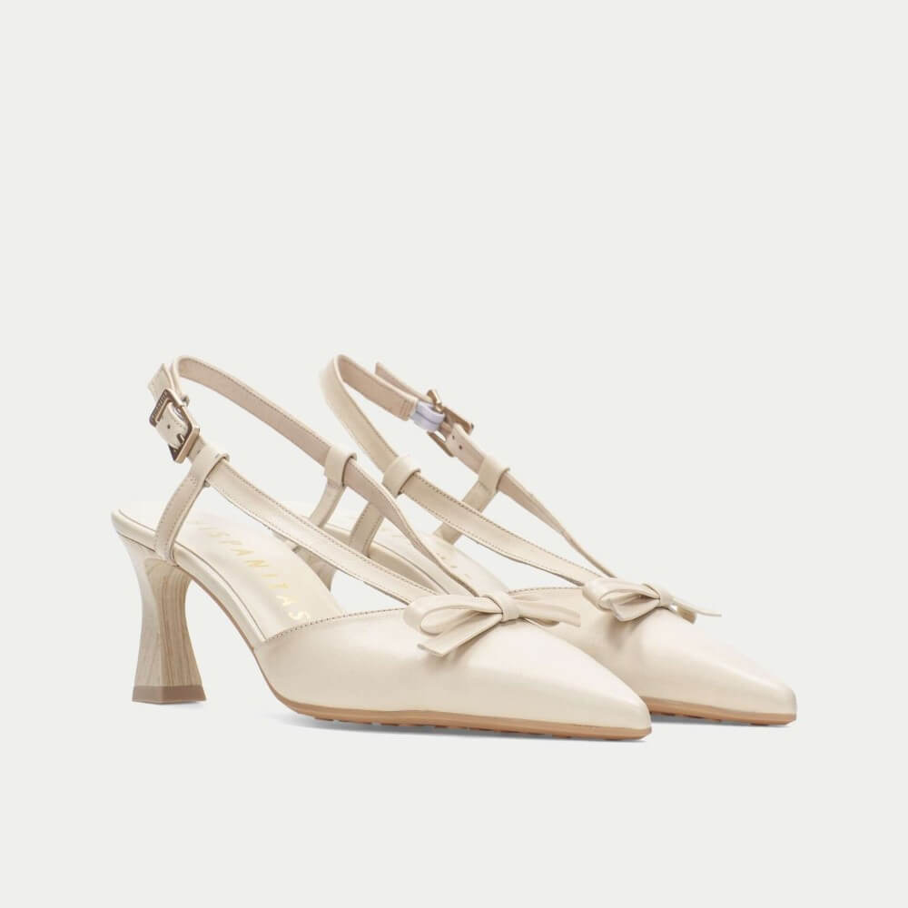 Pair of cream high-heeled shoes with thin straps on a light gray background