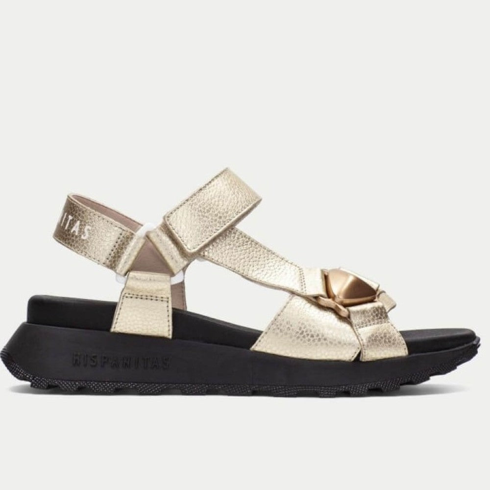 Gold sandal with a black sole on a white background