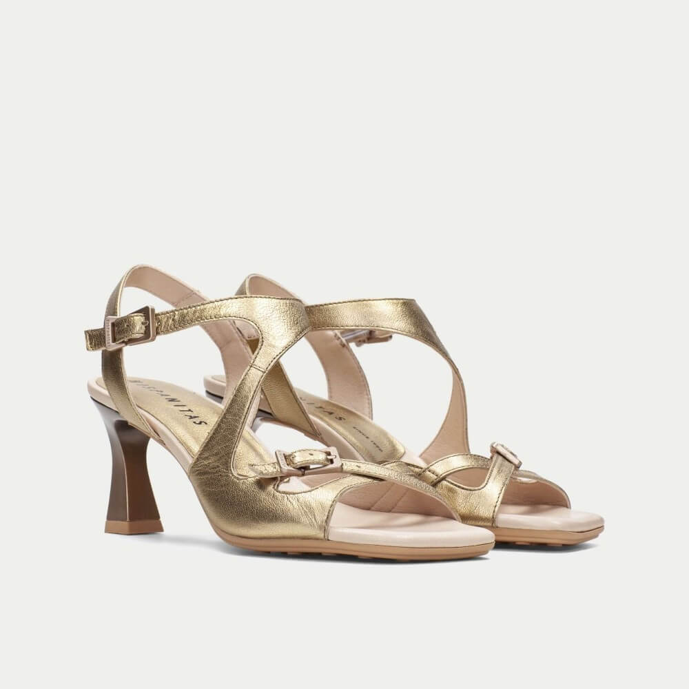 Gold high-heeled sandals on a light gray background