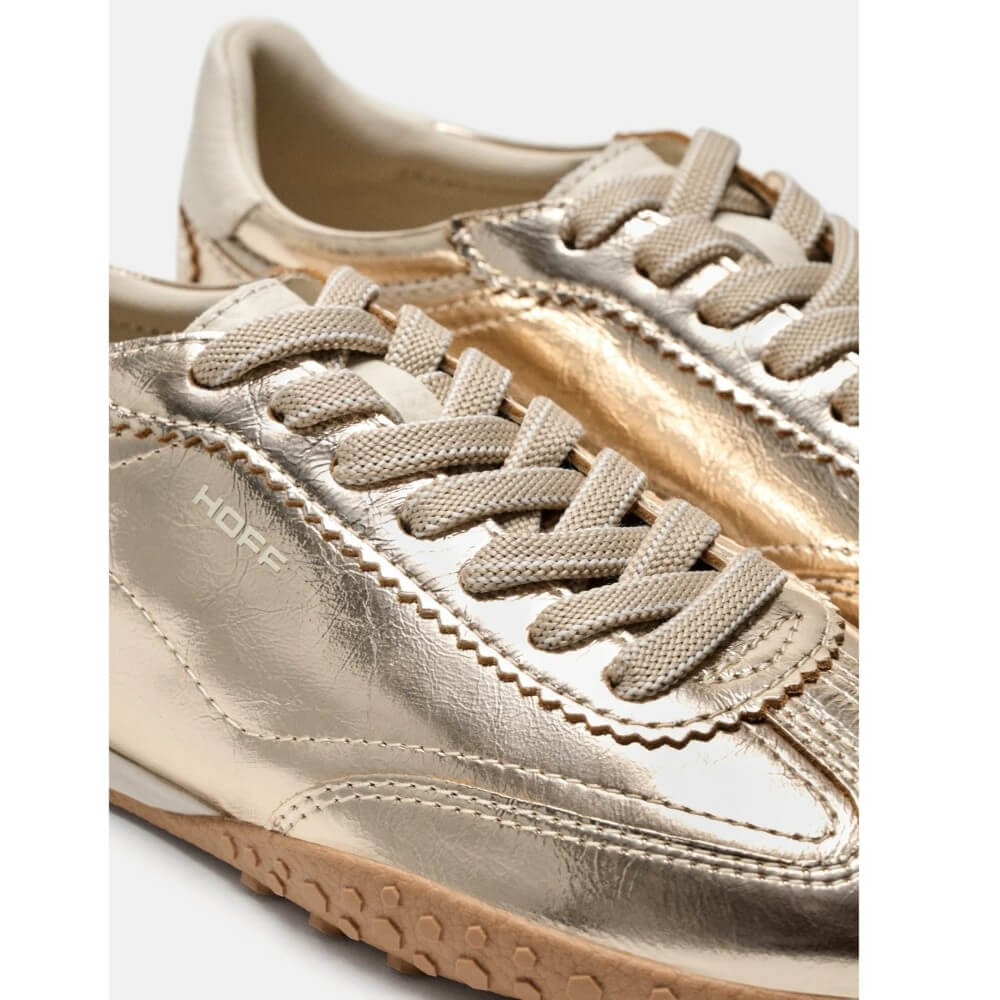 Close-up of Hoff metallic gold low-top sneakers with matching metallic laces and a tan rubber sole, shown on a white background.
