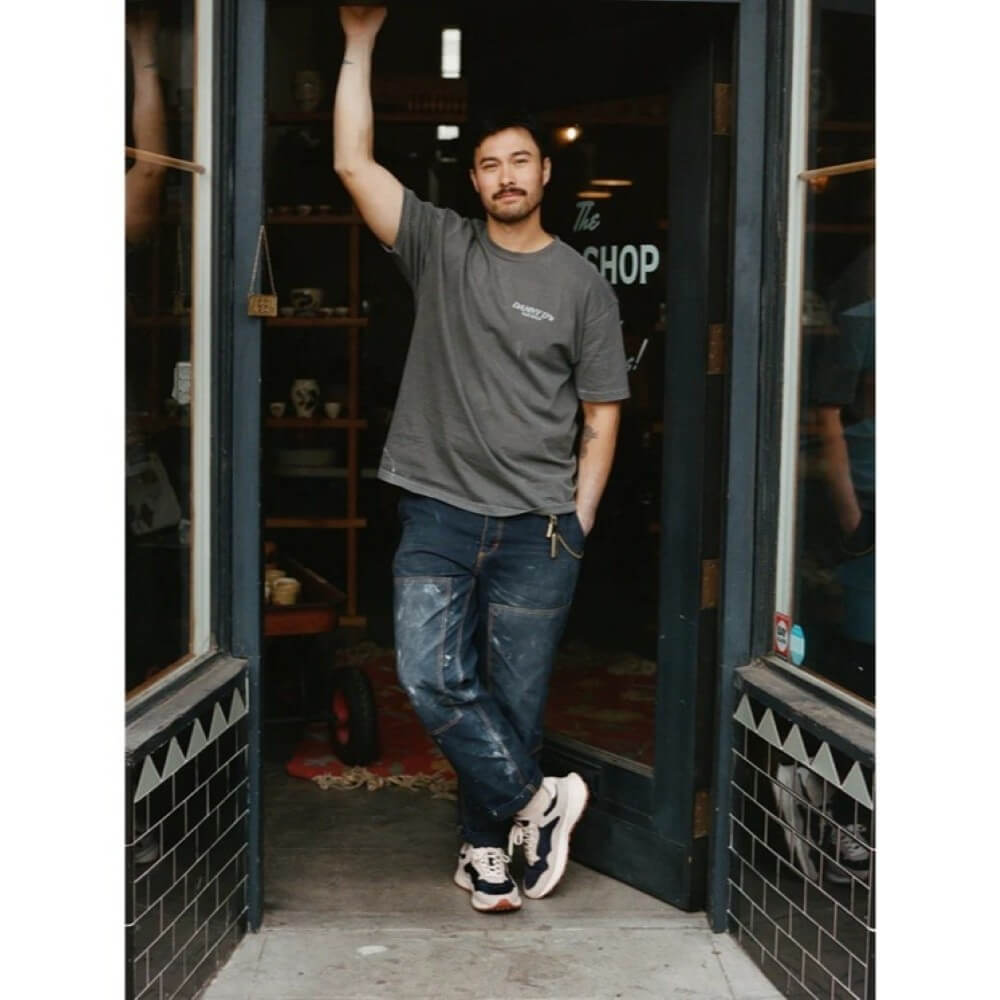 Man Wearing Hoff Sneakers standing in the doorway of a shop with one arm raised
