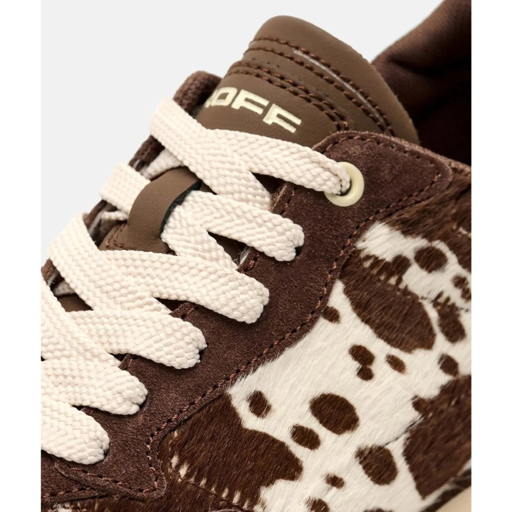 Close-up of a brown suede and cowhide-textured sneaker with off-white laces and a visible 'HOFF' logo on the tongue, set against a light grey background.