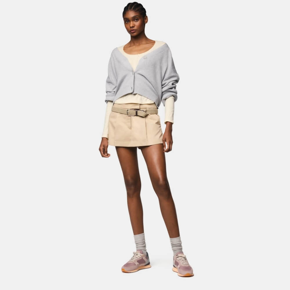 Person wearing a light gray sweater, beige shorts, and pink sneakers on a white background Hoff City Prague