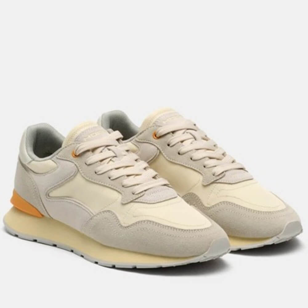 Pair of beige sneakers with orange accents on a light gray background