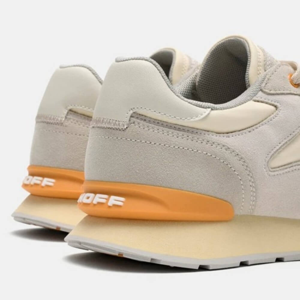 Pair of gray sneakers with orange soles on a light gray background