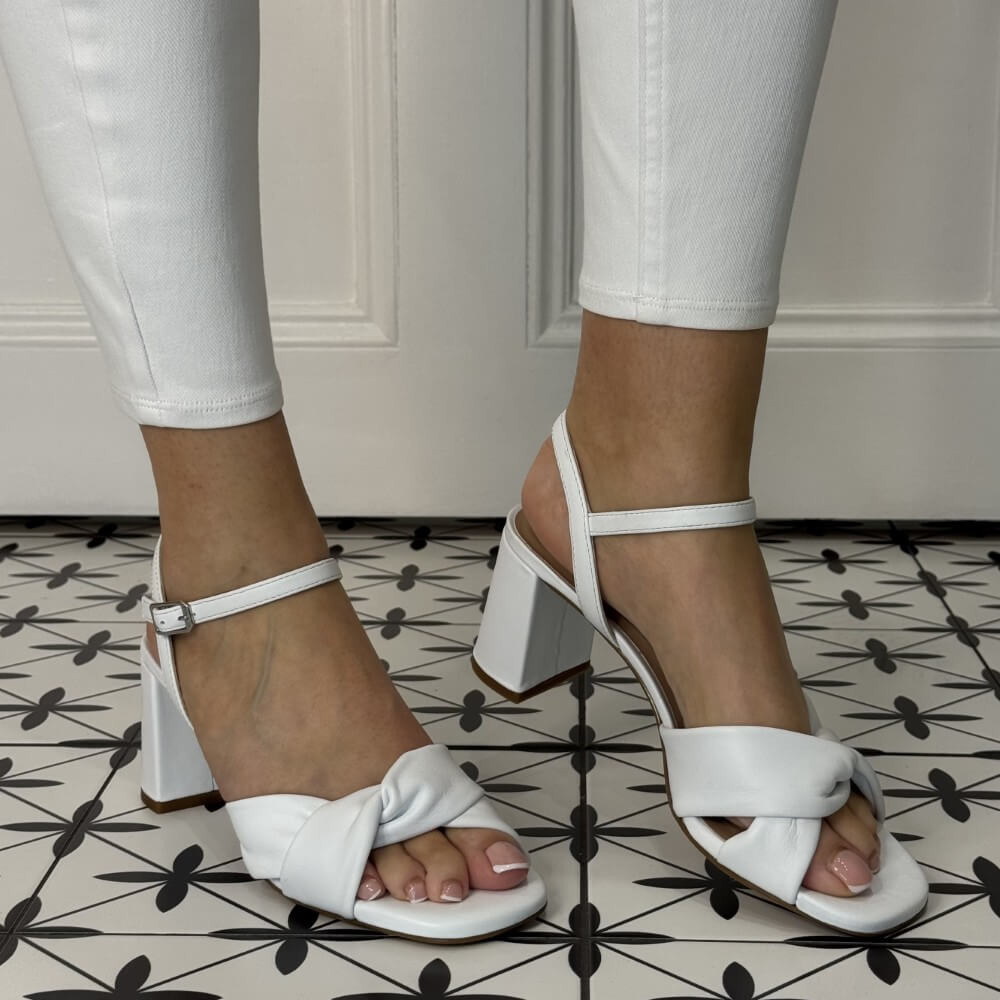 White block-heeled sandals worn with white pants on a patterned floor. unisa medway