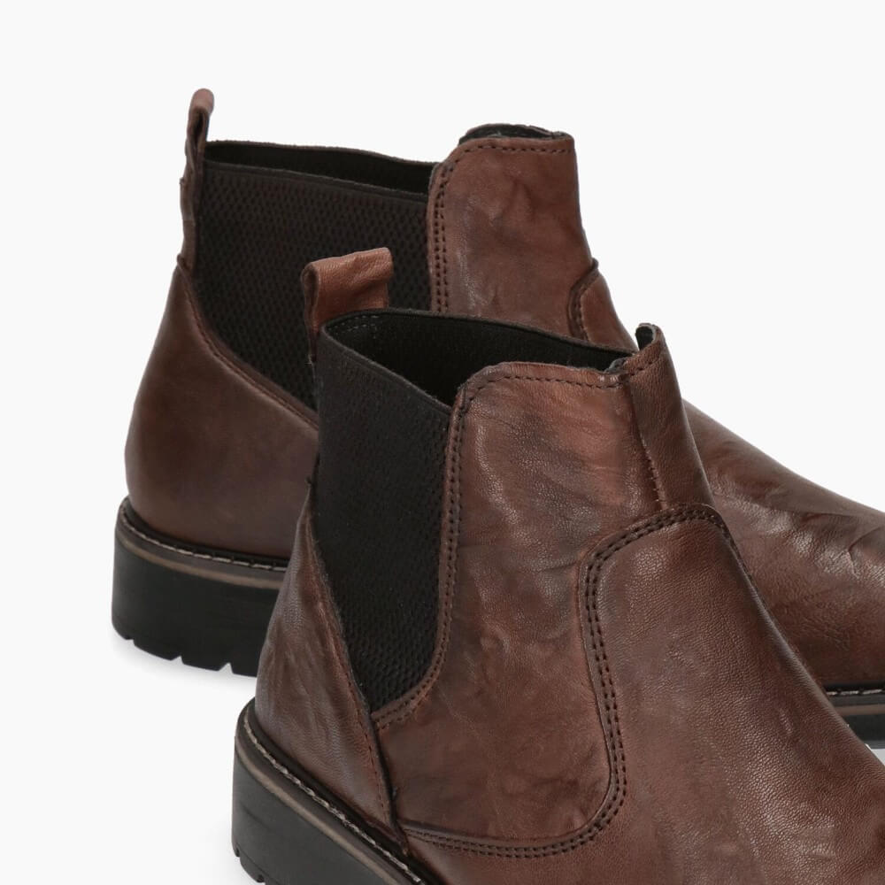 Pair of brown leather boots with black accents on a white background