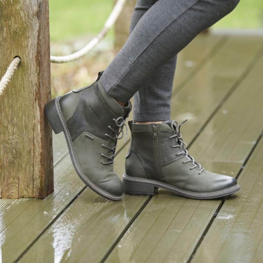 Person wearing green leather boots on a wooden deck
