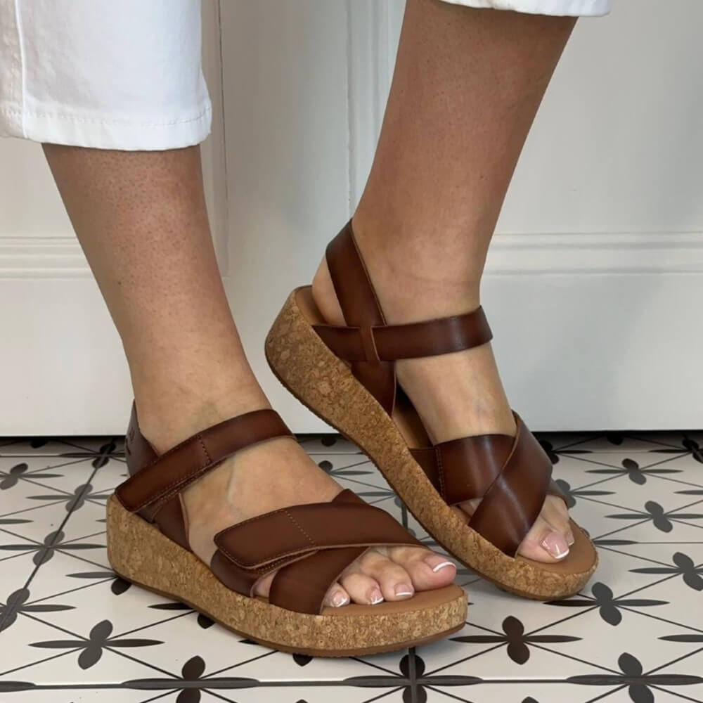 Josef Seibel Brown leather sandals worn by a person on a patterned floor.