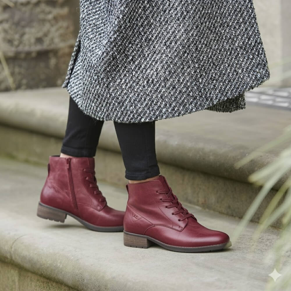Person wearing maroon boots and a long coat sitting on steps.