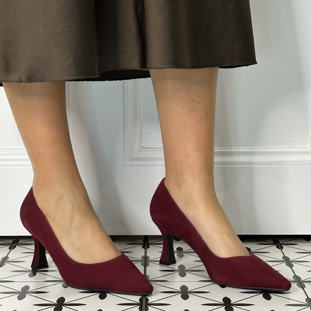 Burgandy suede high-heeled shoes worn by a person on a patterned 
