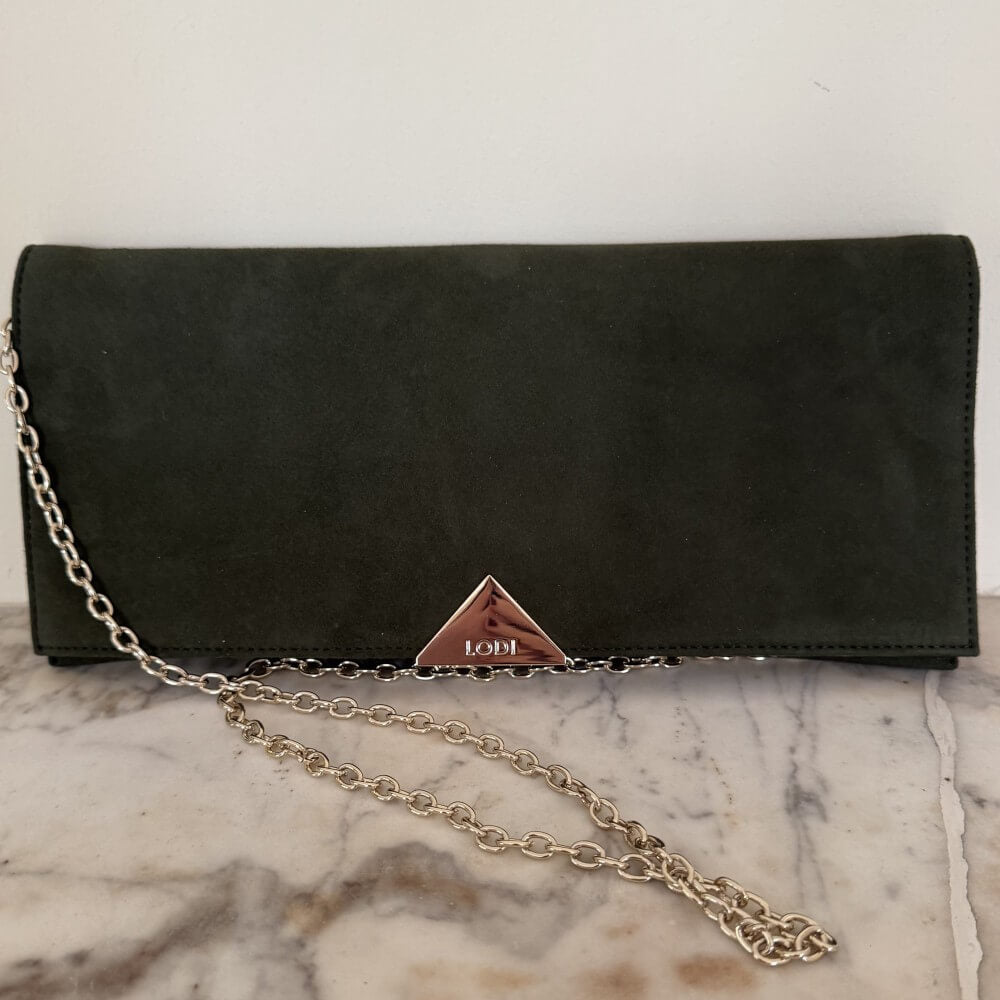 Green suede Lodi clutch bag with gold chain on a marble surface