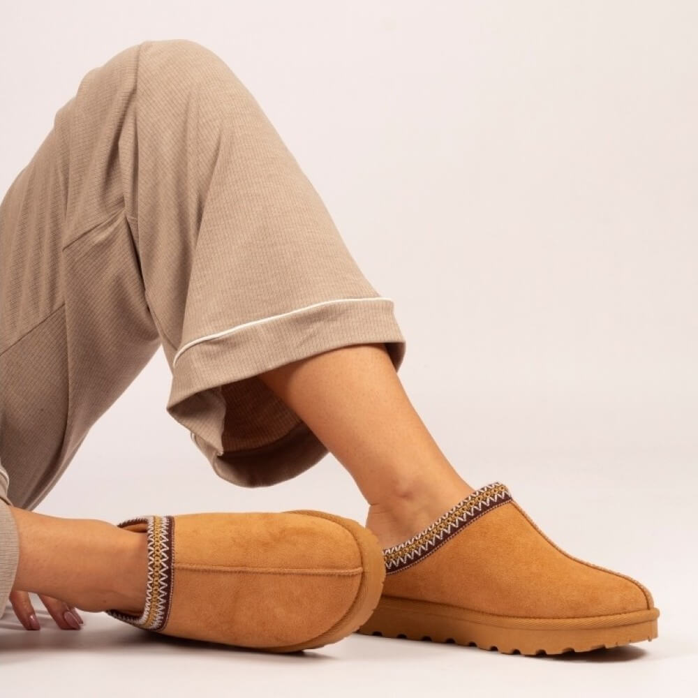 Person wearing a pair of tan slippers