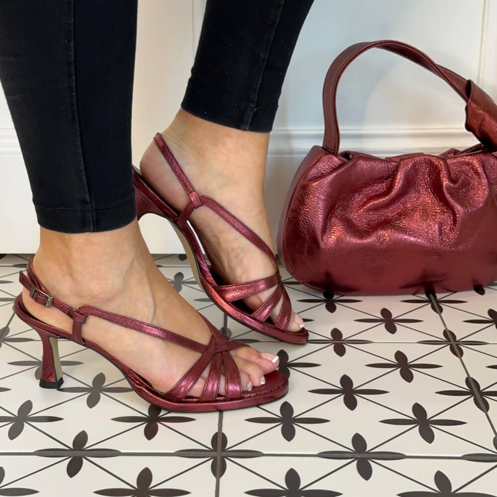 wine Red high-heeled sandals worn with black pants on a patterned floor. MARIAN 53305 Slingback Sandal Burdeos Wine matching bag also