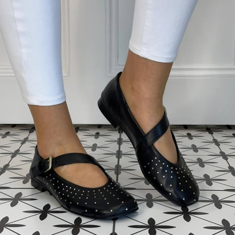 MJUS Black Leather Mary-Jane flat shoes with silver dots worn by a person on a patterned floor.