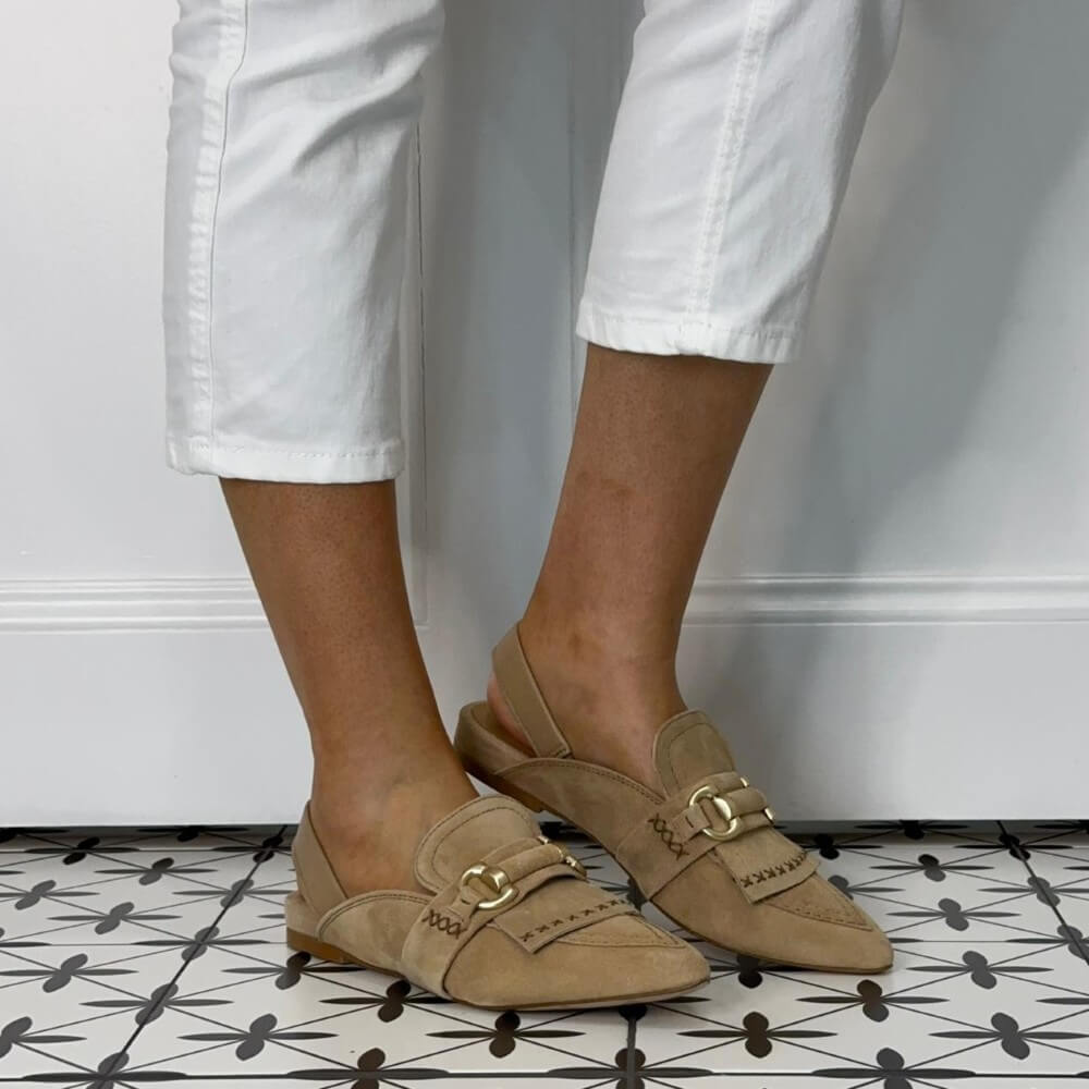 MJUS Beige loafers with gold buckles worn by a person on a patterned floor.