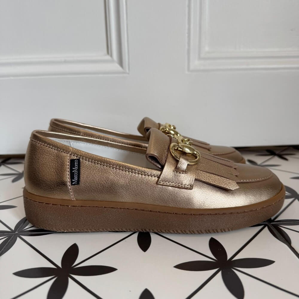 Pair of Marco Moreo  gold bronze loafers with a gold buckle on a tiled floor. X760