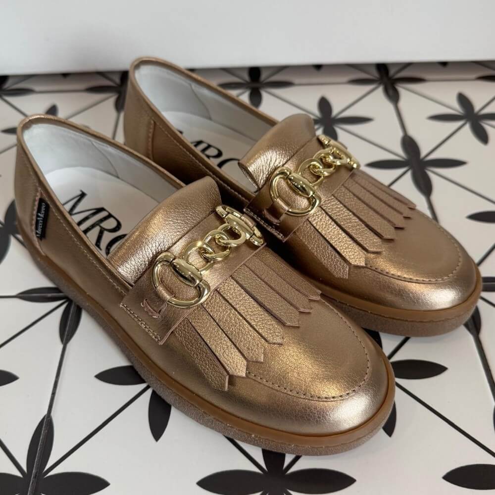 Pair of Marco Moreo  gold bronze loafers with a gold buckle on a tiled floor. X760