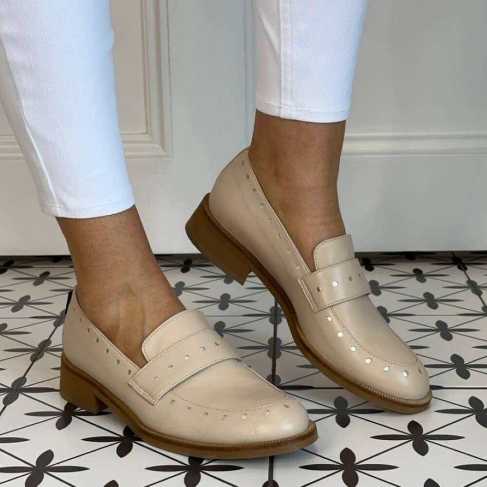 Marco Moreo Beige loafers worn with white pants on a patterned floor.
