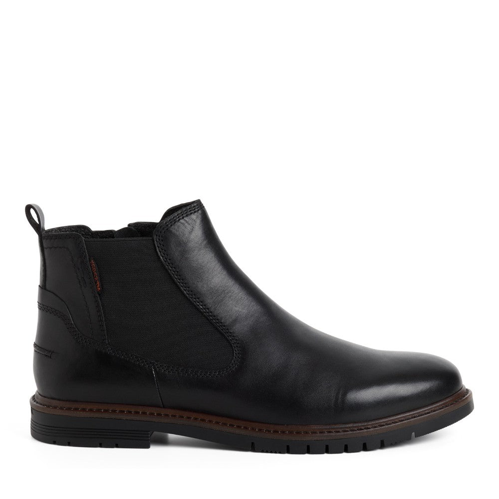 A Marco Tozzi Gents black leather Chelsea ankle boot with a side zipper, elastic side gore, and a brown welt sole, shown in profile against a white background.
