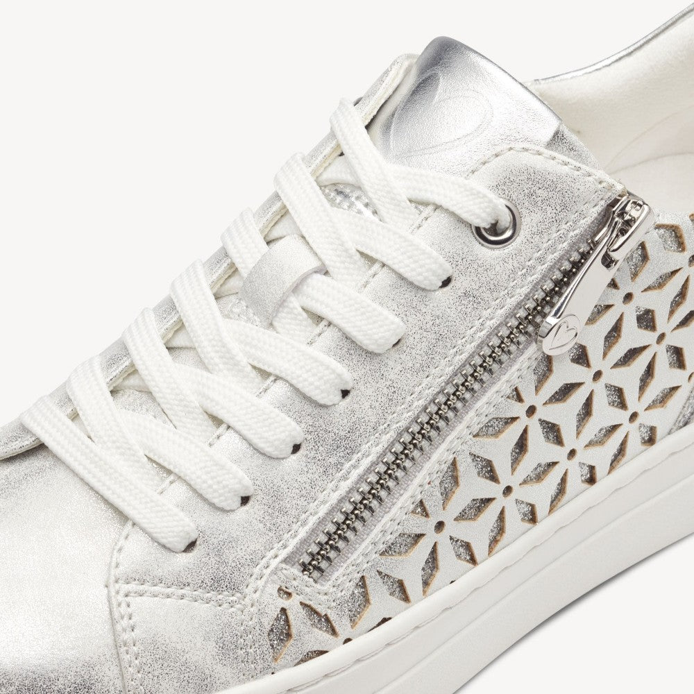 Marco Tozzi Vegan sneaker with silver perforated design on a white background. 