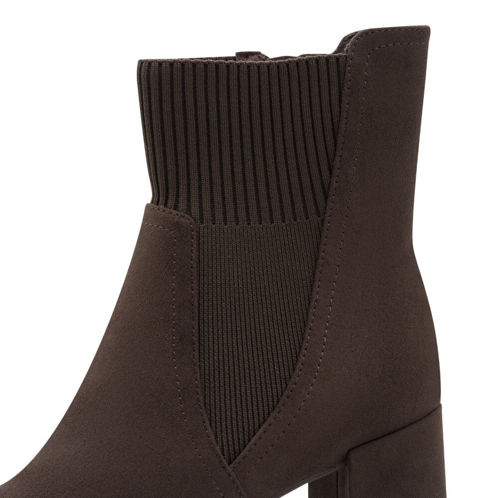 A close-up side view of a dark brown ankle boot with a ribbed knit elastic side panel and a block heel, shown against a plain white background.