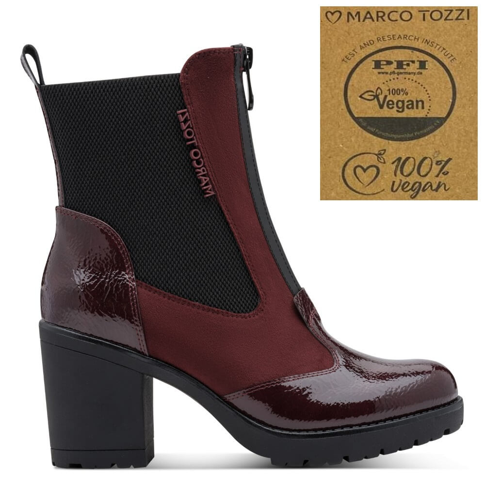 A side-view ankle boot with a glossy deep burgundy and black colorway, featuring a chunky black block heel and a black elastic side panel. A brand badge for 'Marco Tozzi' and a '100% Vegan' certification sticker are shown in the top right corner against a plain white background.