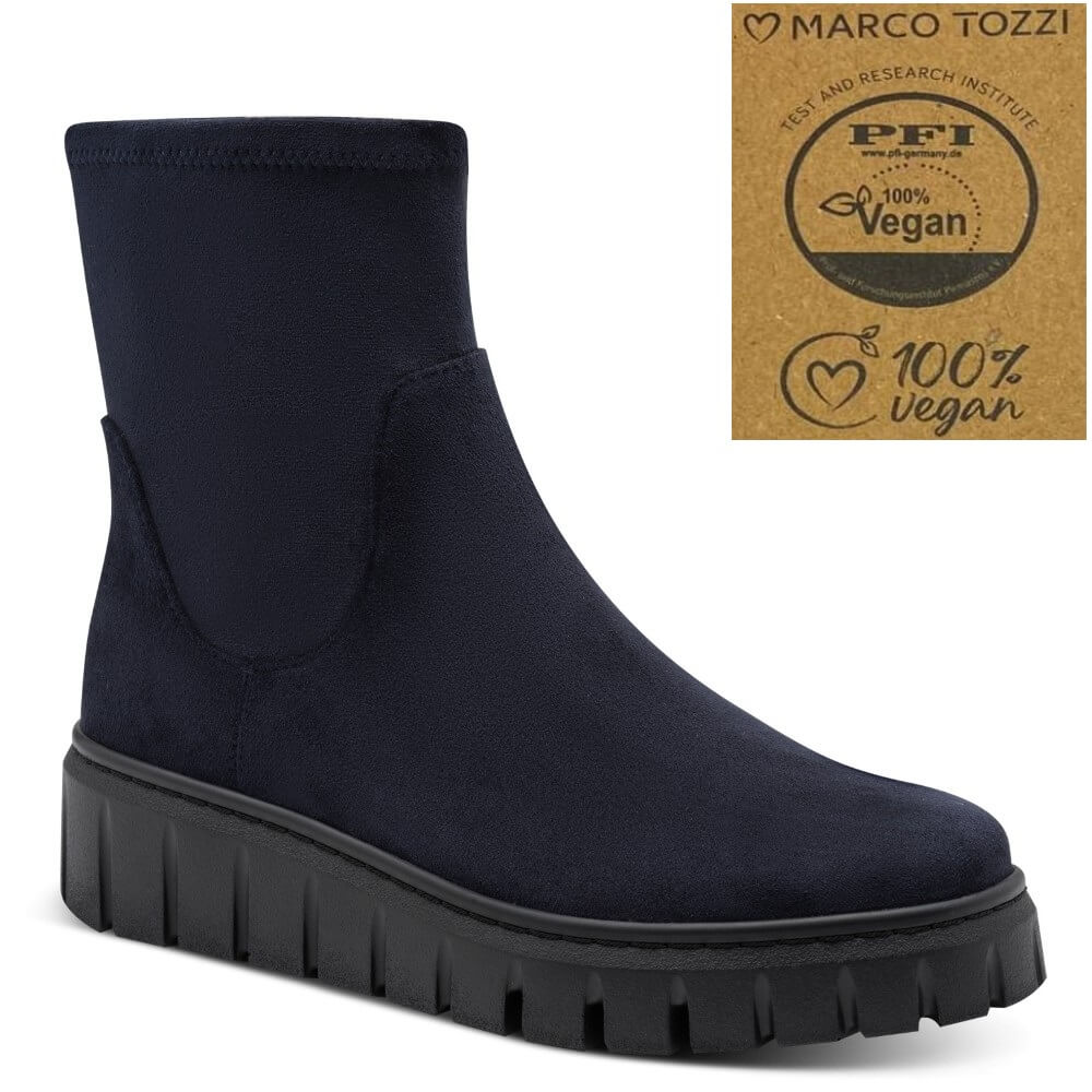 A dark navy blue sock-style ankle boot with a chunky black lug sole, shown on a white background with a 'Marco Tozzi' vegan certification badge in the top right corner.