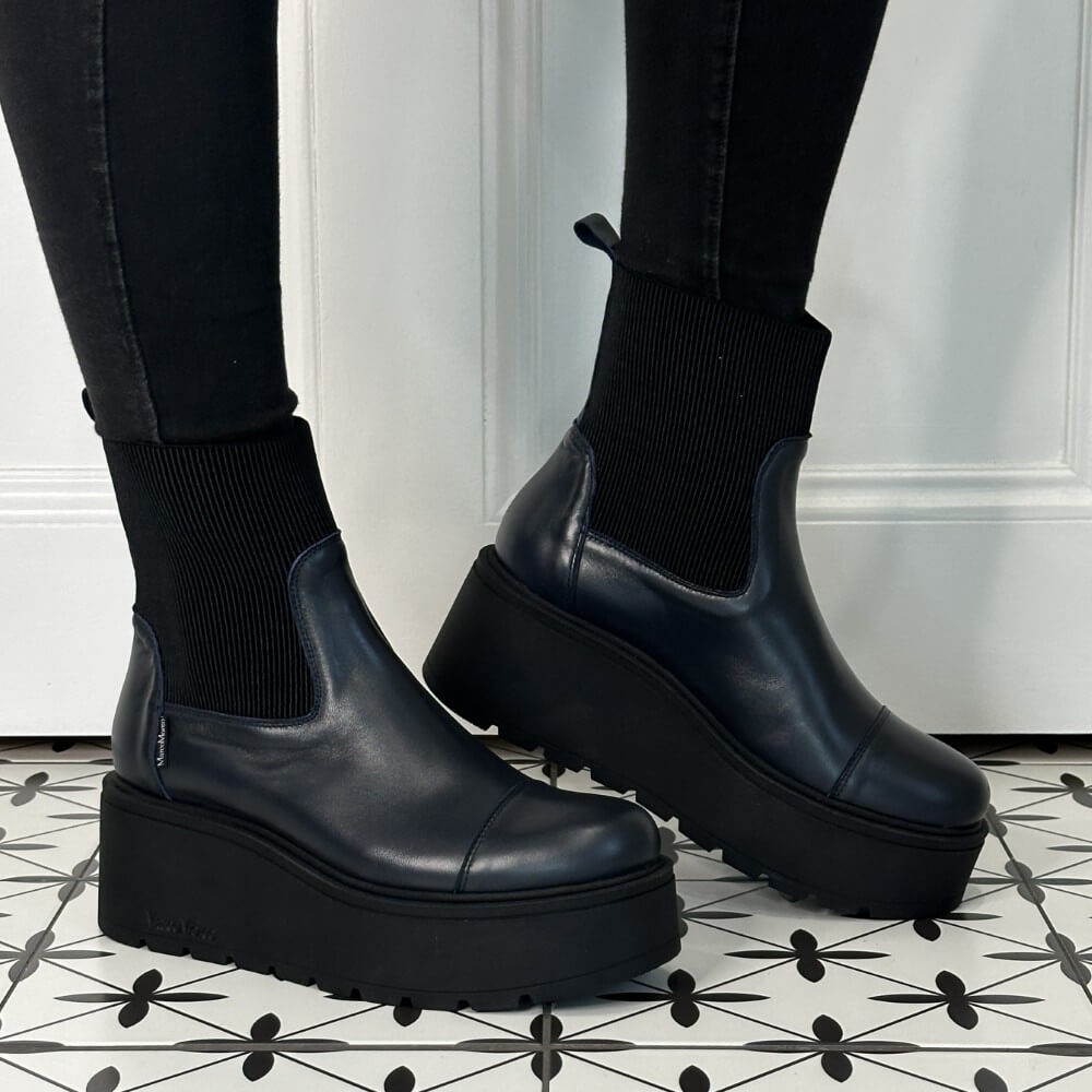 Navy Leather  platform boots worn with black pants on a patterned floor. Marco Moreo A132