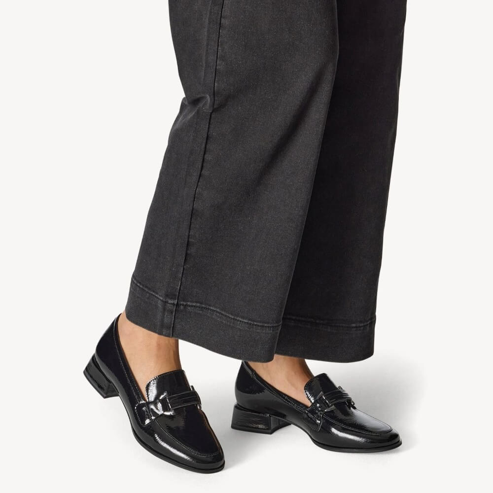 Person wearing black loafers and dark gray pants on a white Marco Tozzi Vegan Loafer 2-24250-BLACKbackground