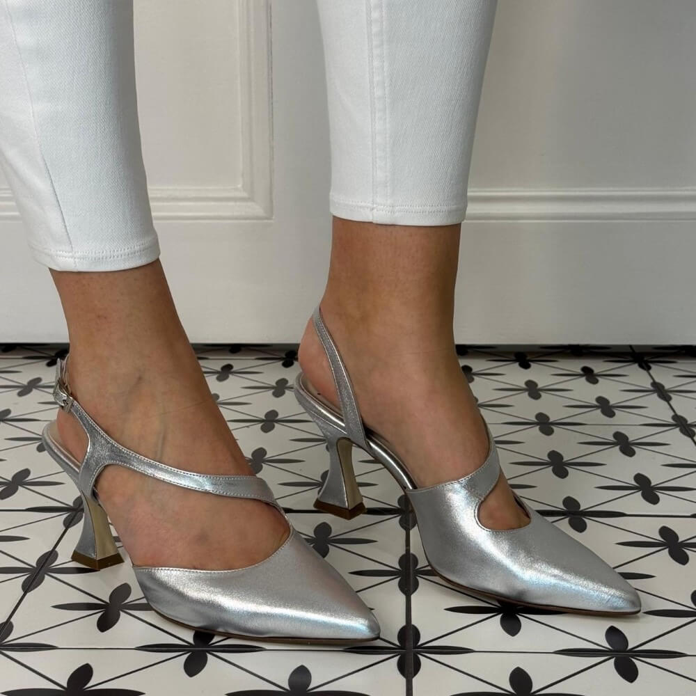 Marian Silver high-heeled shoes worn with white pants on a patterned floor.
