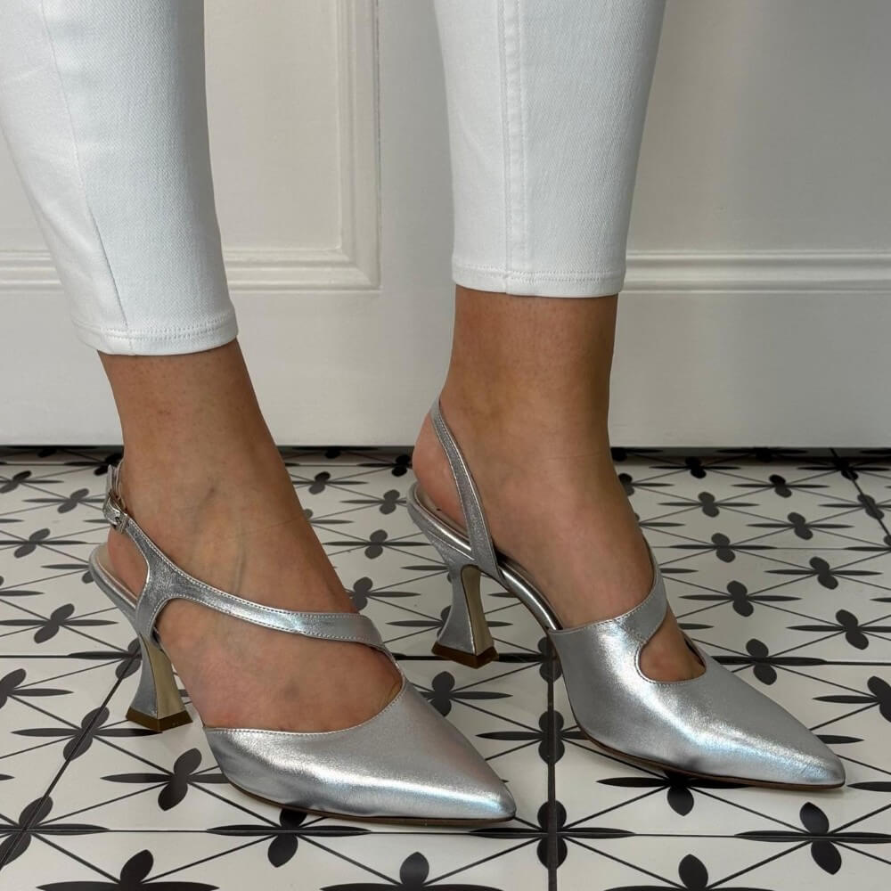 Marian Silver high-heeled shoes worn with white pants on a patterned floor.